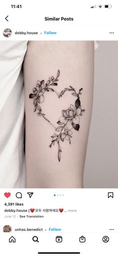 a heart shaped tattoo with flowers on the side of the thigh and an arrow in the middle