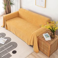 a yellow couch sitting on top of a white rug next to a wooden end table