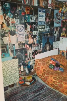 a bedroom with posters on the wall and a bed covered in an orange bedspread