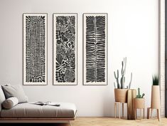 three black and white prints on the wall above a couch in a living room with potted plants