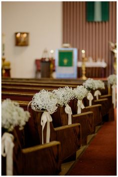 rows of pews decorated with baby's breath flowers and white ribbon tied to them