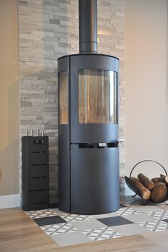 a wood burning stove sitting next to a pile of logs on top of a wooden floor