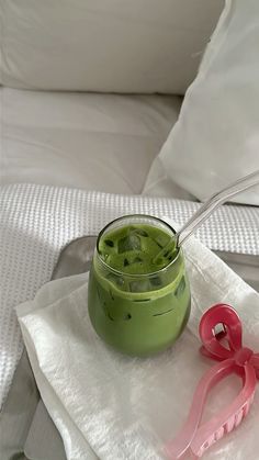 a green smoothie in a small glass with a pink bow on the napkin next to it