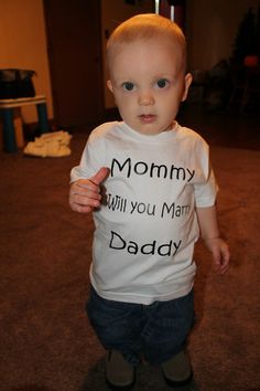 a little boy standing on top of a skateboard wearing a shirt that says mommy will you marry daddy?