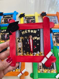 a person holding up a photo frame with graduation decorations on it in front of them