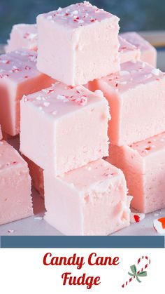 a pile of pink fudges sitting on top of a white plate next to candy canes