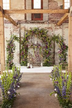 an outdoor ceremony with flowers and greenery on the aisle, surrounded by brick walls