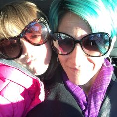 two women with green hair and sunglasses are sitting in the back seat of a car