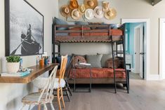 a bunk bed sitting next to a desk and chair in a room with hats on the wall