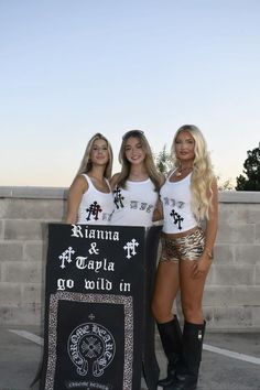 two beautiful young women standing next to each other in front of a chalkboard sign