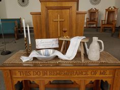 Small stool with wash basin and towel, with water vessel, wooden goblet and pieces of bread with wooden candle stick holders on burlap runner and love one another verse Altar Centerpieces Wedding, Church Altar Decor, Easter Sanctuary Decorations, Church Table Decorations, Pulpit Decorations Church, Communion Table Decorations Church, Church Easter Decorations Sanctuary, Church Communion Table, Easter Church Decorations