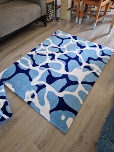 a blue and white rug sitting on top of a wooden floor next to a couch