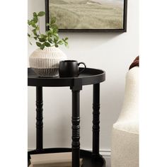 a black table with a white vase and coffee cup on it next to a chair