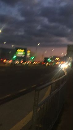 the city street is lit up at night with many lights in the distance and cars driving down the road