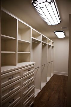 an empty walk in closet with white cabinets and drawers