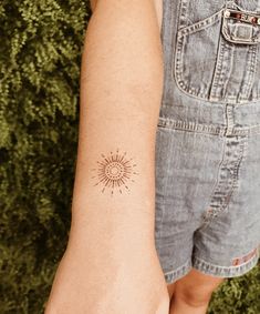 a woman's arm with a small sun tattoo on it