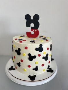 a white cake with mickey mouse decorations on it's top and the letter b