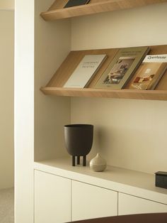 a shelf with some books on it and a vase sitting on top of the shelf