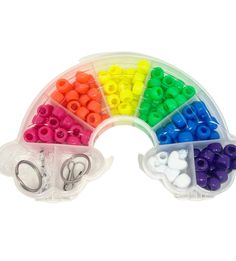 an assortment of plastic beads and scissors in a rainbow shaped case on a white background