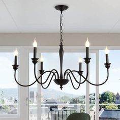 a chandelier hanging from the ceiling in a room with large windows and chairs