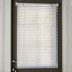 a window with white blinds in front of it and a door handle on the side