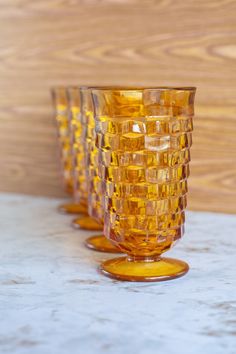 three yellow glass cups sitting on top of a counter