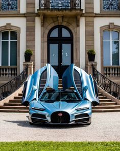 the bugatti supercar is parked in front of a large building with two doors open