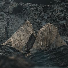 two large rocks sitting on top of a rocky hillside