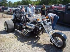 two people standing next to a motorcycle with side car on the ground and another person looking at it