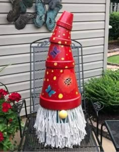 a red and white cone shaped object sitting on top of a metal table next to flowers