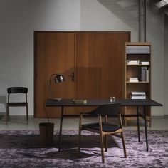 an office with a desk, chair and bookshelf in front of a stair case