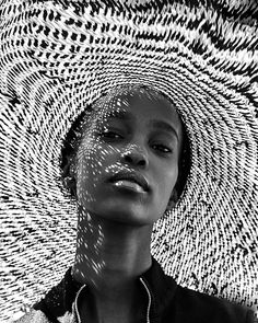 a woman wearing a large straw hat with her face partially obscured by the sun's shadow