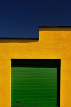 a yellow building with a green garage door