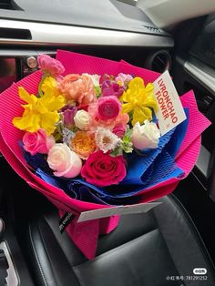 a bouquet of flowers sitting on top of a pink car seat cover in a vehicle