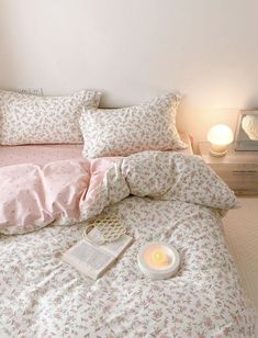 a white bed with pink sheets and pillows on top of it next to a night stand