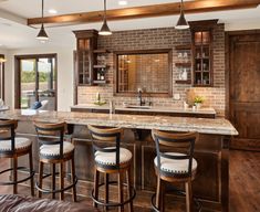 a kitchen with an island and bar stools in front of the counter top area