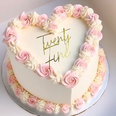 a heart shaped cake with pink and white frosting roses in the shape of a heart