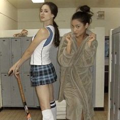 two young women dressed in school uniforms and holding baseball bats, standing next to lockers