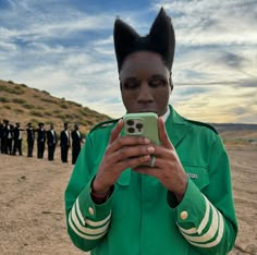 a man in a green uniform is holding a cell phone and taking a selfie