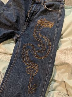 a pair of jeans with embroidered dragon on them