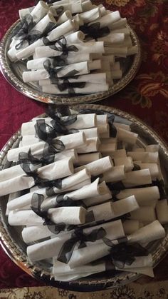 two trays filled with white and black napkins on top of a red table cloth