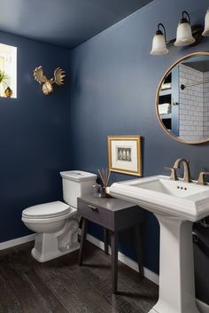 a white toilet sitting next to a sink in a bathroom under a mirror and lights