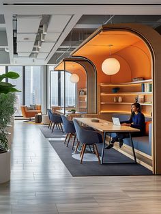 a person sitting at a table with a laptop in an open office space that looks like a library