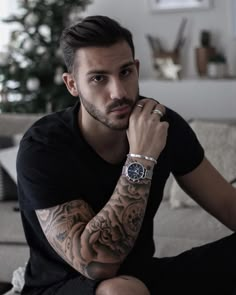 a man with tattoos sitting on a couch