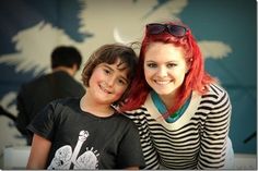 a woman with red hair sitting next to a boy wearing black and white striped shirt