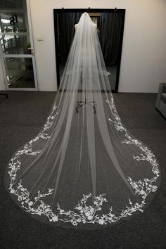 a wedding veil with white flowers on the bottom is sitting in front of a doorway