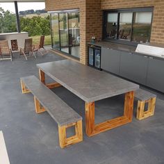 a concrete table and benches in front of a brick building with large sliding glass doors