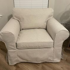 a white chair sitting on top of a hard wood floor next to a window with blinds