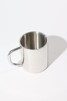 a stainless steel cup with handle on a white background, viewed from the bottom to the side