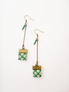 the earrings are decorated with green and white squares, beads, and silver chain links